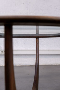 La table Astro est un meuble emblématique de la marque anglaise de mobilier G-Plan, qui a été produite pour la première fois en 1969. Elle a été conçue par Victor Wilkins et est devenue l'une des créations les plus populaires de G-Plan, avec son design futuriste caractéristique et son utilisation de matériaux de qualité. La table Astro est une table basse ronde en teck avec un plateau en verre circulaire. Elle repose sur un pied central en bois sculpté qui s'étend en quatre branches courbées pour soutenir le plateau en verre. Le design organique du pied rappelle les formes des années 60, évoquant l'ère spatiale et le futurisme de l'époque.